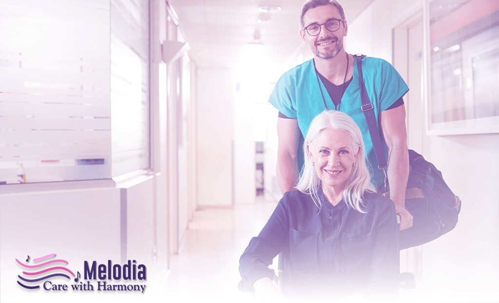 A caregiver joyfully assisting an elderly hospice patient into a wheelchair at the time of discharge, both wearing smiles of happiness.