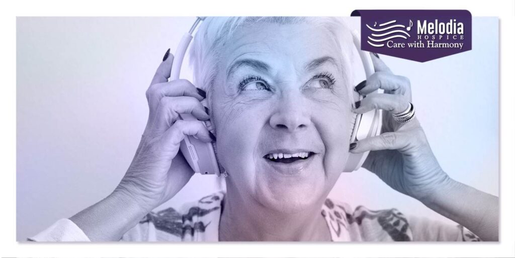 An elderly hospice patient, a woman, is listening to music. She is sitting in a comfortable chair and a serene expression on her face.