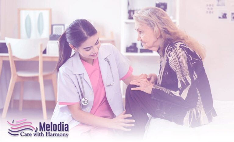 Young nurse sitting in front of old lady, gently holding her legs during routine care.