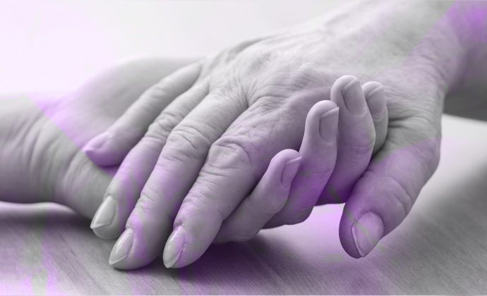 Interlocking hands symbolizing palliative care between elderly woman and caregiver